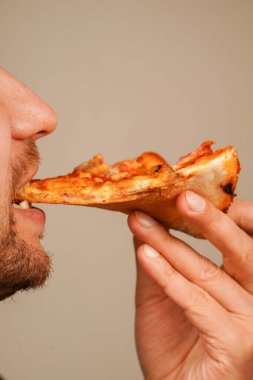 Bir adamın elinde peynirli ve pepperonili iştah açıcı pizza. Fast food, günlük yemek ve açlık kavramları için bir konsept.