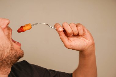 Taze hazırlanmış külçeler, çatalla şişlenmiş, tadını çıkarmaya hazır, fast food 'un zevkini sembolize ediyor. Külçeler ketçapla kaplanmış.