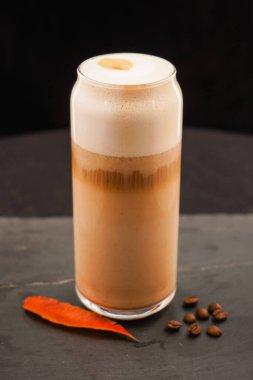 Güzel bir fincanda latte macchiato izole edilmiş siyah bir arka planda ve lezzetli bir kahveyle. Şeffaf cam bardakta kapuçino köpüklü süt içeceği. İçecek tarifi