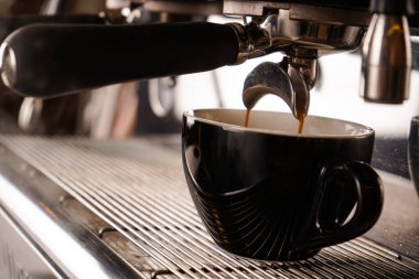 Siyah bir fincanda espresso hazırlayan modern bir kahve makinesinin işi. Çok aromatik bir içki.