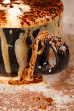 Yumuşak, sıcak kakao yavaşça fincanın kenarından dökülür, erimiş çikolata damlaları gibi. Kapat.