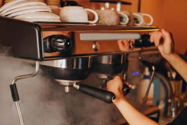 Sakin ve sakin, barista köpüren sütten sonra buhar çubuğunu siler, her içkinin kusursuz olmasını sağlayan detaylara dikkat eder.