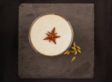 Bir bardak chai tea latte, tarçınlı sıcak latte köpüklü garnitür, kırsal ahşap arka planda köpüklü süt içmek, üst manzara.
