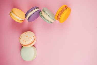 Pembe arka planı olan parlak ve renkli badem kurabiyeleri. Bu ikonik Fransız ziyafetleri lezzet, doku ve zanaatkarlığın hoş bir kutlamasıdır.