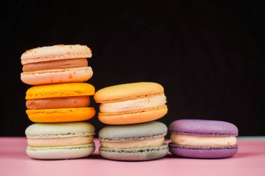 Çok renkli badem kurabiyeleri bir piramide istiflenmiş. Sarı, yeşil ve pembe badem kurabiyeleri zarif bir şekilde bir kaydırağın içine istiflenir. Tatlının tadı ve kalitesi gözler önüne serilir.