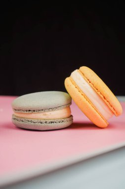 Çok renkli Fransız badem kurabiyeleri. Pembe arka planda düzgünce yerleştirilmiş. Mutfak sanatı ve tatlılığın mükemmel bir kombinasyonu hassas dokularını ve parlak gölgelerini vurguluyor.