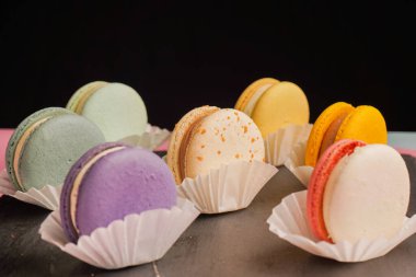 Siyah arka planda çok güzel yapılmış çok renkli makaronlar var. Fransız kaynaklı enfes hamur işleri ve tatlıların sunumu.