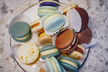 Elegant selection of assorted macarons in different pastel colors. Close-up highlights the texture of the dessert filling. As a concept for French cuisine, desserts and confectionery themes clipart