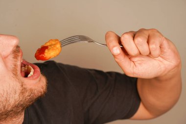 Taze hazırlanmış külçeler, çatalla şişlenmiş, tadını çıkarmaya hazır, fast food 'un zevkini sembolize ediyor. Külçeler ketçapla kaplanmış.
