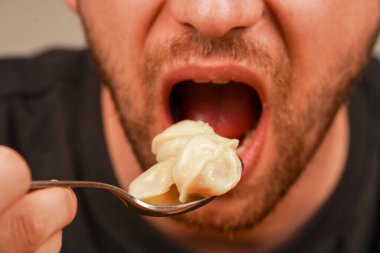 Adam mantı buğulamayı seviyor, kaşıkla kendine yardım ediyor. Yemek pişirmek ve yaşam tarzı kavramları için harika