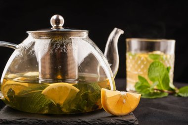 Bitkilerle siyah çay demleme süreci, siyah çay ile cam çaydanlık, siyah çay, limon, kireç ve kaynayan suda ıslatılmış nane, buhar çaydanlığın üzerinde yükselir.