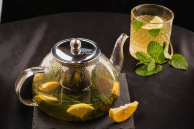 Süslü desenleri olan bir Fas çaydanlığı yumuşak ışık altında parıldıyor. Zarif, siyah bir arka planda dinleniyor.