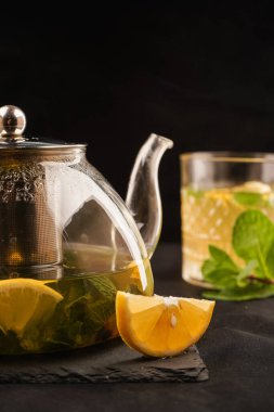 Limonun pürüzsüz, parlak teni şeffaf çaydanlıkla çok güzel tezat oluşturuyor. Bir sürü çayın döküldüğü bir yer. Siyah arkaplan