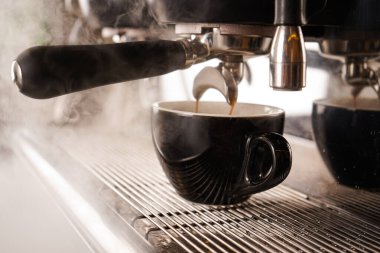 Kahve makinesinden kahve fincanına dökülen Americano 'nun yakın çekimi. Sade kahve yapan profesyonel bir kahve.