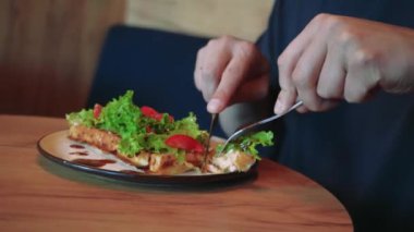 Fırında Belçika waffle 'ı ile yakın plan bir tabak domates ve soslu marul yaprakları. Sıcak bir kafedeki ahşap bir masada lezzetli bir tabak kahvaltı var.