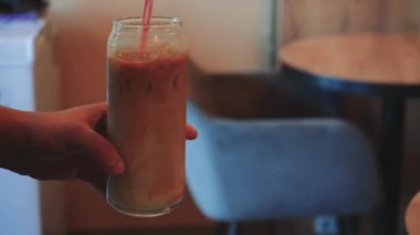 Ferahlatıcı bir içecek ve yeşil bitkiler sıcak ortamı geliştirir. Açık kahverengi saçlı ve sakallı bir adam küçük, rahat bir kafe masasında Belçika waffle 'ı yiyor.