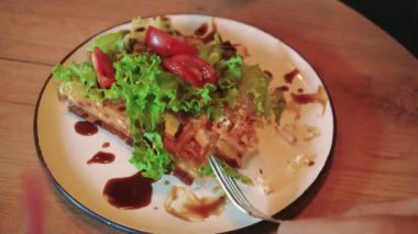 Fırında Belçika waffle 'ı ile yakın plan bir tabak domates ve soslu marul yaprakları. Sıcak bir kafedeki ahşap bir masada lezzetli bir tabak kahvaltı var.