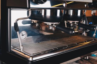 Profesyonel bir siyah kahve makinesi kafeteryada bir masanın üzerinde duruyor. Sıcak bir yere yakın çekim