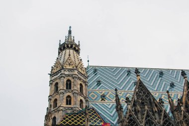 Viyana, Avusturya - 12 Mayıs 2019: Avusturya 'daki St. Stephens Katedrali' nin üst kısmı, yakın çekim fotoğrafı. St. Stephens Katedrali Viyana şehrinin simgesi ve simgesidir. Zigzag kiremit çatı