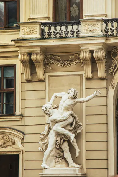Viyana, Avusturya - 12 Mayıs 2019 Klasik bina cephesi yakınında mimari detaylar içeren heykel. Dinamik mücadelede iki kaslı erkek figürünü gösteren dramatik mermer heykel.