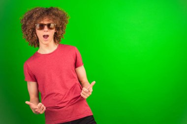 Şehvetli bukleleri ve parlak gözlükleri olan bir çocuk, yeşil krom anahtar arka planına karşı durarak, multimedya projeleri için çok yönlü ve adapte edilebilir bir görsel varlık sağlayarak sakince bakıyor.