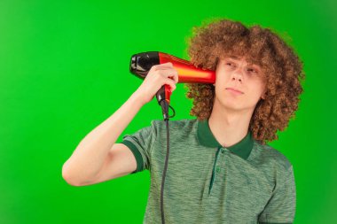 Neşeli bir sırıtışla, genç adam kendisine bir saç kurutma makinesi, hareket eden gömleği ve kıvırcık saçlarıyla Chroma Key 'in düzeneğini güçlendiriyor.