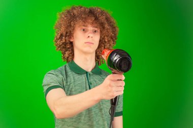 Chroma Key yeşili, adam sahnede yaratıcı bir şekilde saç kurutma makinesi kullanırken gömleğinin ve saçının hareketini vurgular.