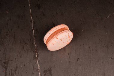 Pastel renkli badem kurabiyeleri, siyah arka planda. Sarı badem kurabiyeleri siyah bir masada yatar. Reklam tatlıları ve şekerlemeler için harika.