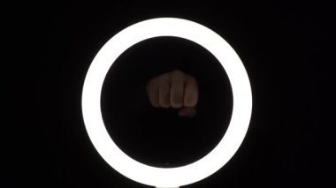 Kadın elleri çerçevede bir yumrukla vuruyor. Kadın hakları için savaş. Siyah arkaplanda yakın plan hareketler.