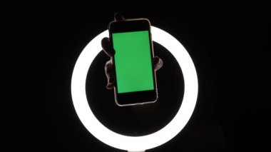 Kadın eli, telefonun siyah arka planda yakın çekimini gösteriyor. Reklam eklemek için yeşil ekran modeli. Parmakları ekranda gezdirir, tıklatmalar, kaydırmalar, yazılar.