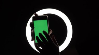 female hands show the phone close-up on a black background. green screen mockup for advertising insert. Moves fingers across the screen, taps, swipes, types.