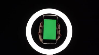 Kadın eli, telefonun siyah arka planda yakın çekimini gösteriyor. reklam eklemek için yeşil ekran modeli.