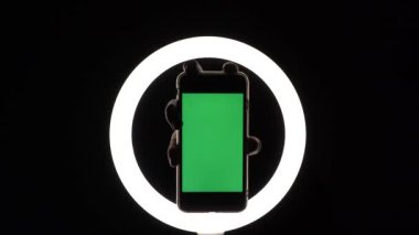 Kadın eli, telefonun siyah arka planda yakın çekimini gösteriyor. reklam eklemek için yeşil ekran modeli.