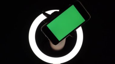 Kadın eli, telefonun siyah arka planda yakın çekimini gösteriyor. reklam eklemek için yeşil ekran modeli.