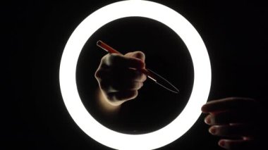 female hands hold a ballpoint pen with a cap close-up on a black background. Tool for blogger, student, copywriter, writer.
