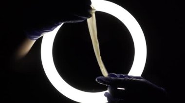 female hands in blue rubber latex gloves open, unfold, stretch and test the strength of a condom close-up on a black background. protection against sexually transmitted diseases and contraception.