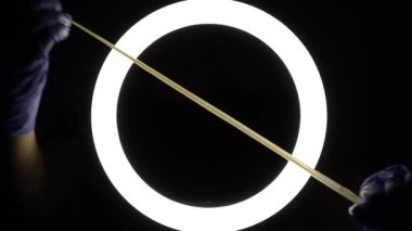 female hands in blue rubber latex gloves open, unfold, stretch and test the strength of a condom close-up on a black background. protection against sexually transmitted diseases and contraception.