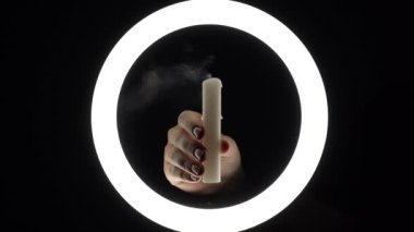 female hands extinguish a candle close-up on a black background. burning fire on a candle stick. The concept of ritual actions.