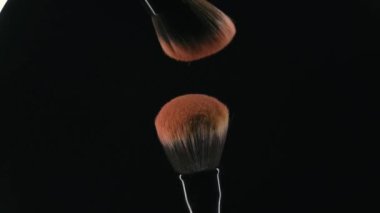 Makyaj fırçası barutu havaya uçuruyor. Yavaş çekimde toz bulutuna dönüşen toz patlaması. güzellik konsepti makro.