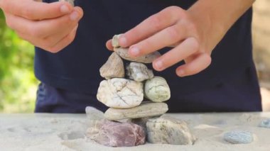 man builds a pyramid of sea stones. heap of smooth pebbles. zen stones close-up. the concept of peace of mind and relaxation in the resort.