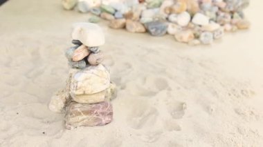 Kum, deniz taşlarından oluşan bir piramidin üzerine dökülür. Yumuşak çakıl yığını. Zen taşları yakın plan. Huzur ve dinlenme konsepti..