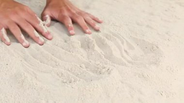 Beyaz deniz kumlarında erkeklerin elleri akın eder. Sahil oyunları. Deniz kıyısındaki kumu okşar. Tatil kavramı.