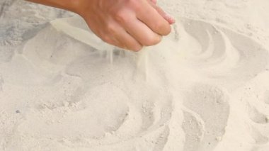 Beyaz deniz kumlarında erkeklerin elleri akın eder. Sahil oyunları. Deniz kıyısındaki kumu okşar. Tatil kavramı.
