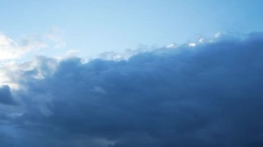 Gökyüzündeki gri bulutlar hızla hareket ediyor. Güneş ışınları bulutları delip geçer. Bulutlu hava.