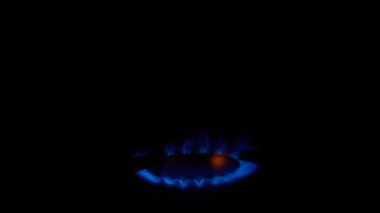 Mutfak ocağındaki gaz ocağı yanıyor. Siyah arka planda, karanlıkta yanan mavi ateş alevi. Doğal gaz iltihabı. Doğal enerji taşıyıcısı, fosil yakıt.