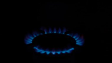Mutfak ocağındaki gaz ocağı yanıyor. Siyah arka planda, karanlıkta yanan mavi ateş alevi. Doğal gaz iltihabı. Doğal enerji taşıyıcısı, fosil yakıt.