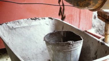 Beton karıştırıcı bina karışımını karıştırıyor ve bir kovaya döküyor. Dönüşümlü inşaat aleti yakın çekim. Gri yapım yapıştırıcılı inşaat işi.