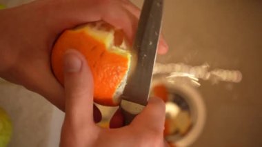 Bir temizlikçinin elleri mutfak lavabosundaki portakal kabuğunu temizler. Üst manzara 4K. Düzgün beslenme, sağlık hizmetleri.