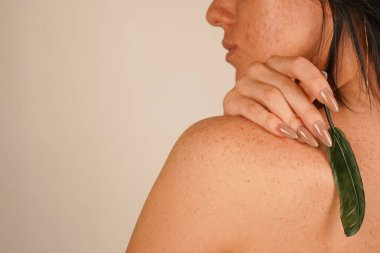 Siyah saçlı bir kız nazikçe sırtını küçük bir tüyle okşar. Onun çıplak sırtı doğal güzelliği ve kadınlığı ön plana çıkarıyor. Bej rengi pastel duvar resme yumuşaklık ve zarafet katar.