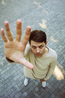 Yüksek bir bakış açısından, bir adam kaldırım taşlı bir caddede duruyor. Bakış açısı, kentin hareketli ortamındaki konumunu vurguluyor. Şehir manzarası ana derinlik katıyor.